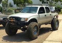 an off road truck parked on the side of a street next to a fenced in area