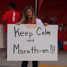 a woman holding a sign that says keep calm and marathon on