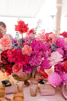 a vase filled with pink and red flowers sitting on top of a white table cloth