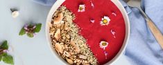 a bowl filled with granola and fruit on top of a blue cloth next to a spoon