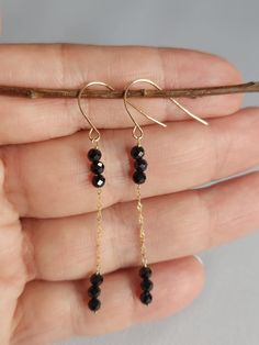 A pair of super chic, minimalist black spinel drop earrings crafted in 14k yellow gold. They measure 5.4cm from top to bottom and have a combined weight of 0.92g.  These earrings have a set of French hooks which are hallmarked 14k. The chain that connects the two gold bars is a very fine and sparkly Singapore chain. Three spinel beads are strung on each gold bar.  These earrings are part of a new old stock that I acquired. They have never been worn. There is 1 bead that is slightly chipped (see Minimalist Black Linear Earrings As Gift, Minimalist Black Linear Earrings For Gifts, Black Dangle Jewelry With Gold Beads, Elegant Everyday Jewelry With Black Spinel, Minimalist Black 14k Gold Earrings, Minimalist Black Spinel Necklaces, Elegant Beaded Black Spinel Jewelry, Classic Black Spinel Jewelry, Black Spinel Jewelry