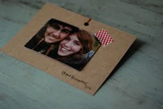 a couple's photo hanging on a brown card with a red checkered heart