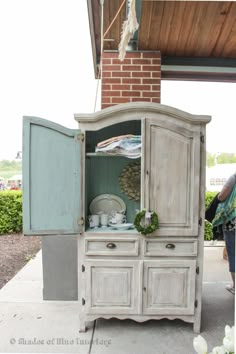 an old china cabinet is painted white and has been turned into a hutch for storage