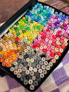 an open case filled with lots of different colored crayons on top of a checkered table cloth