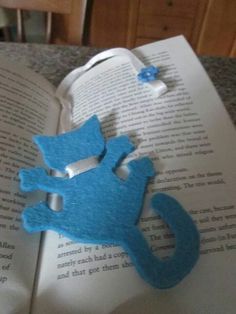 a blue cat brooch sitting on top of an open book