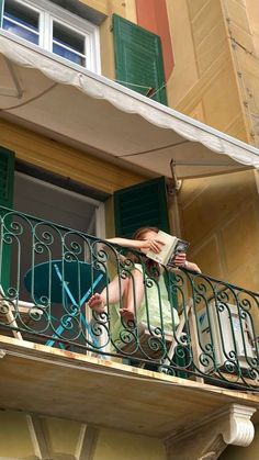 a woman sitting on a balcony reading a book