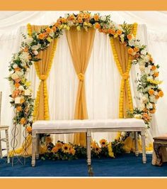 an arch decorated with flowers and yellow drapes