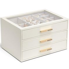 a white jewelry box with three drawers and gold handles on the bottom, filled with rings