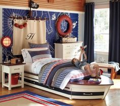 a boy is laying on his bed in the middle of a room with blue curtains