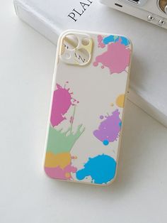 an iphone case with paint splattered on it and a camera next to it