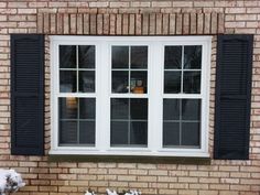 a brick building with black shutters and snow on the ground