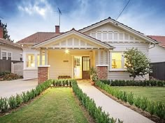 a house that is in the middle of some grass and bushes on the front lawn