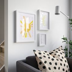 a living room filled with furniture and pictures on the wall next to a stair case