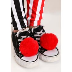 a pair of black and white sneakers with red pom - poms