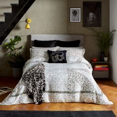 a bed sitting under a stair case next to a table with a lamp on it