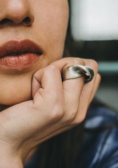 a close up of a person with a ring on their finger and her hand near her face