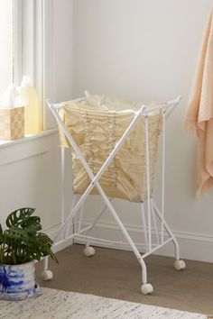 a white ironing board sitting on top of a floor next to a potted plant