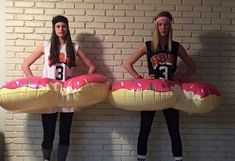 two girls standing next to each other with donuts in front of their faces on giant pillows