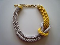 a yellow and white bracelet with two gold clasps on a white surface, next to a silver chain