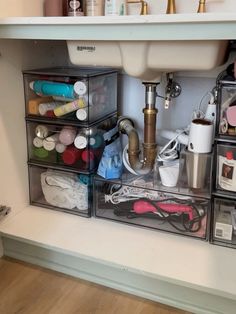 an organized bathroom under a sink with lots of crafting supplies in bins on the counter