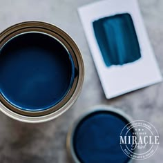 two cans of blue paint sitting on top of a table next to a white box