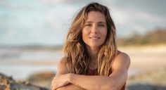 a woman sitting on the beach with her arms crossed