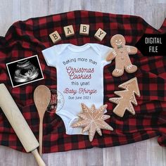 baby's first christmas bodysuit, cookie cutters and other items laid out on a plaid blanket