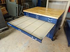 two drawers are stacked on top of each other in a garage with workbenches