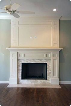 an empty living room with a fireplace and ceiling fan