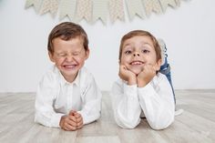 two young boys laying on the floor with their hands under their chins and smiling