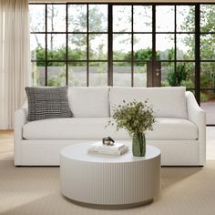 a white couch sitting next to a table with a vase on it's end