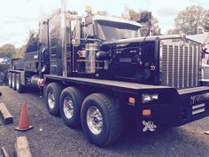 a large semi truck parked next to an orange cone on the side of the road