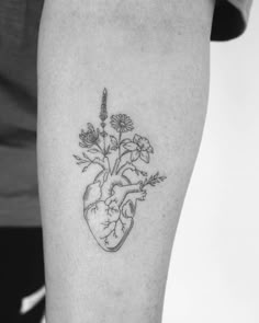 a black and white photo of a heart with flowers on the inside of it's arm