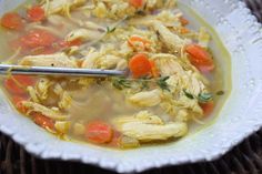 a white bowl filled with chicken and carrots on top of a wicker table