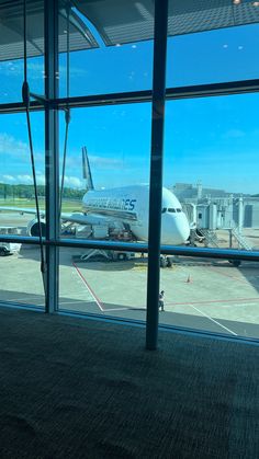 an airplane is parked at the airport and it's reflection in the glass window