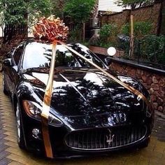 a black sports car with a gold ribbon tied to it