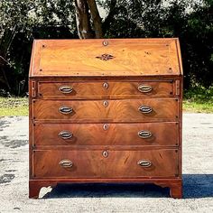 an old wooden chest of drawers sitting in front of a tree