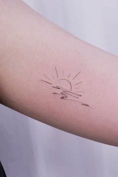 a woman's arm with a small sun tattoo on the left side of her arm