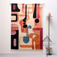 a colorful rug hanging on the wall next to a lamp and floor lamp in a room