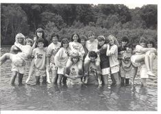 a group of young people standing in the water with their arms around each other,