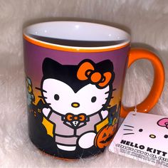 a hello kitty coffee mug with an orange handle and black interior sits on a white furnishing