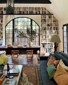 a living room filled with lots of furniture and bookshelves next to a window