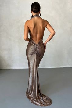 the back of a woman in a gold dress with her hands on her hips, looking down