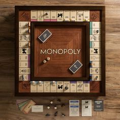 the monopoly board game is displayed on a wooden table with cards and other items around it