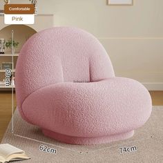 a pink chair sitting on top of a rug next to a book