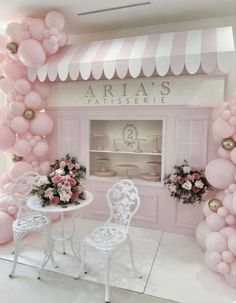 a room decorated with pink balloons and white chairs