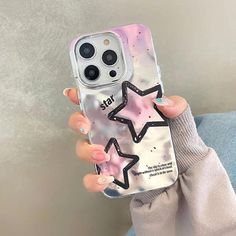 a woman holding up her phone case with stars on it