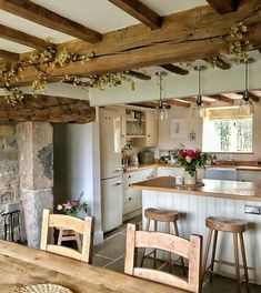 a kitchen with wooden tables and stools next to a stone fireplace in the center