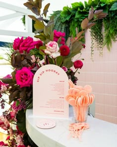 pink flowers and greenery are displayed on a table