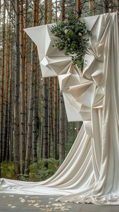 an art installation in the woods with white fabric draped over it's face and trees